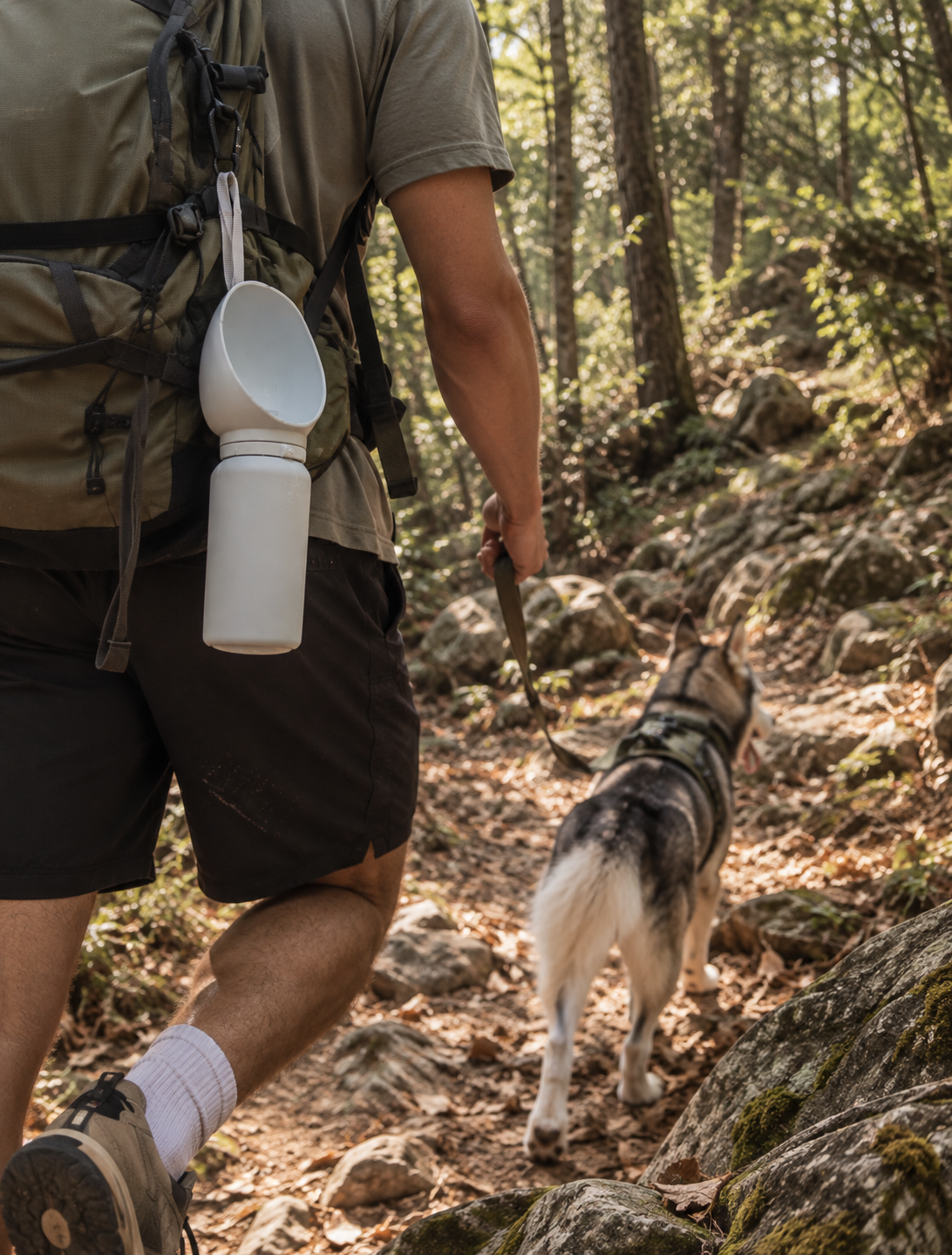 Hiker carrying the white Wayloa Collapsible Dog Water Bottle clipped to a backpack
